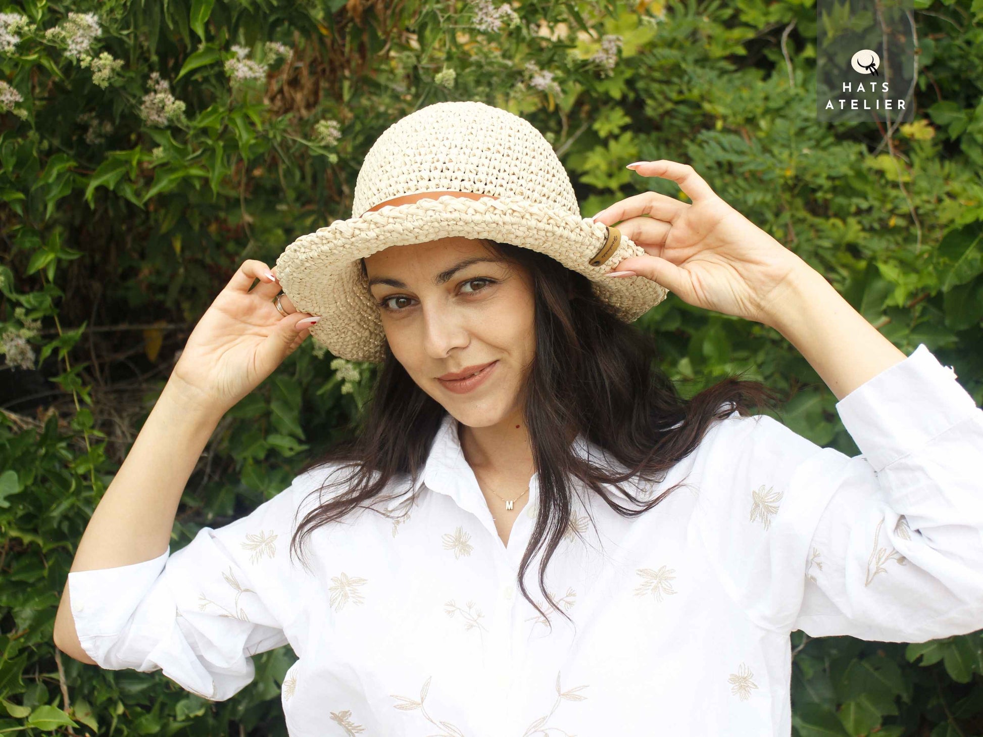 Boho crochet raffia straw hat with medium brim worn by woman outdoors