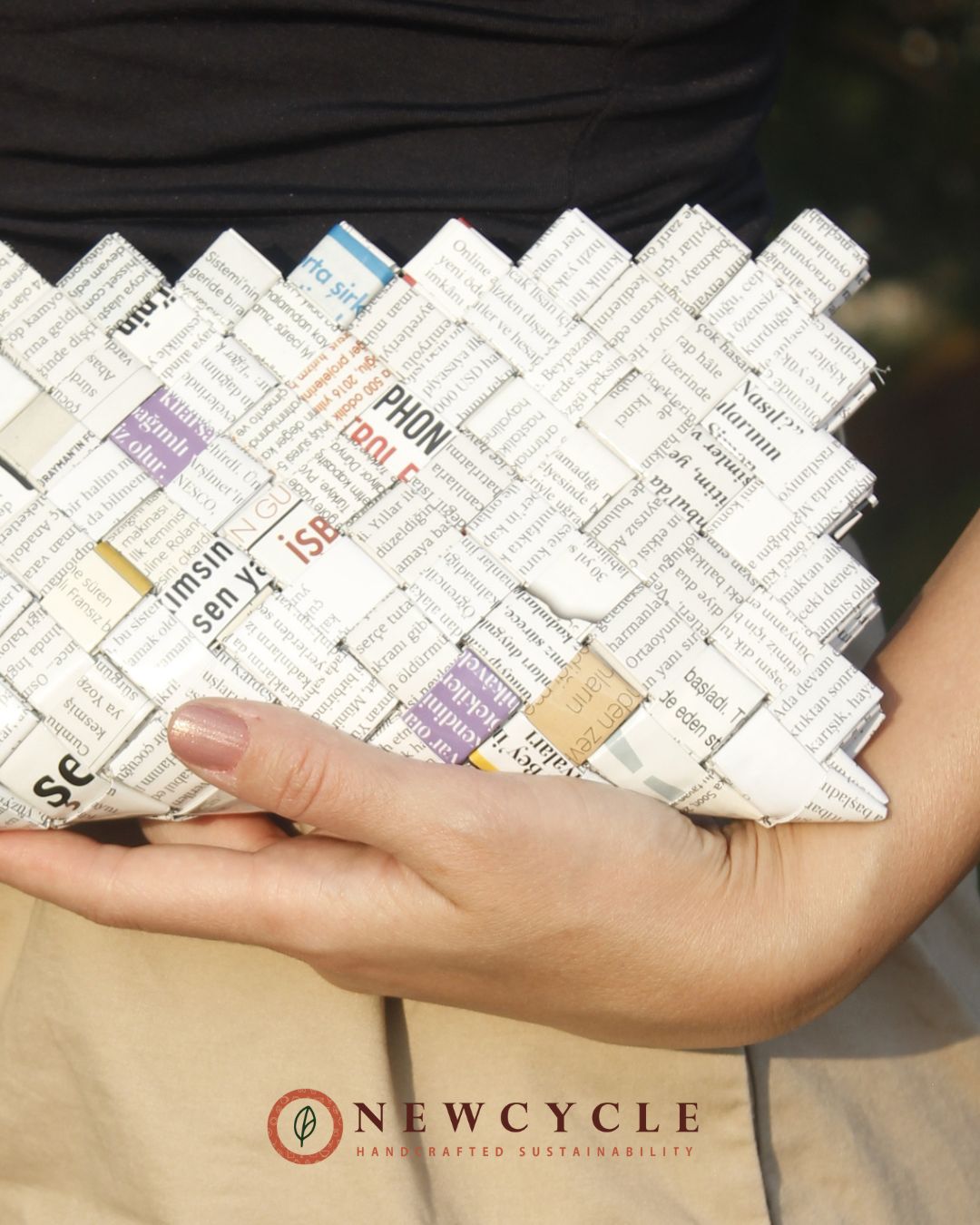 Hands holding eco friendly newspaper-print clutch with white mosaic pattern