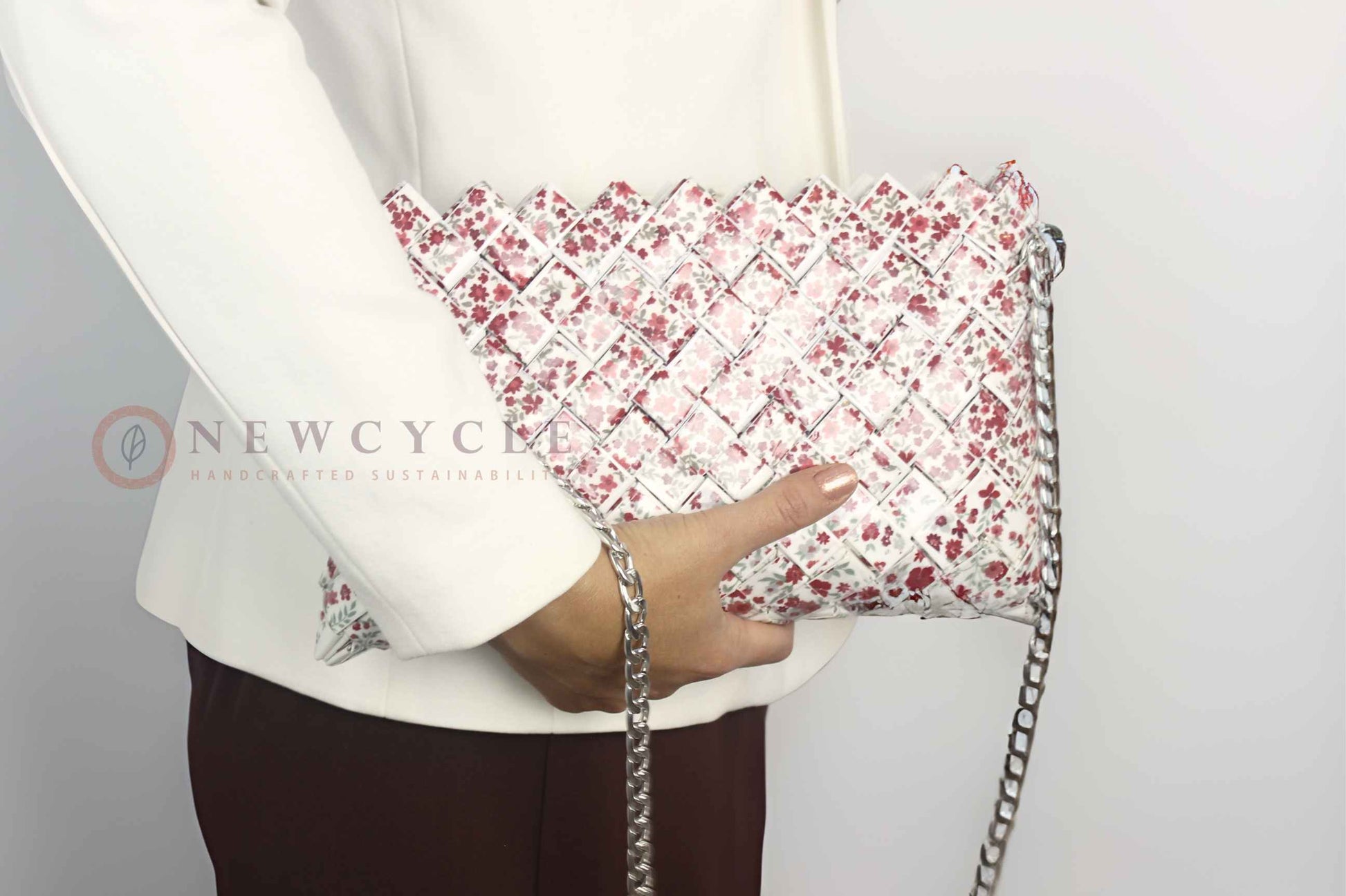 Woman holding a red floral woven shoulder bag with silver chain