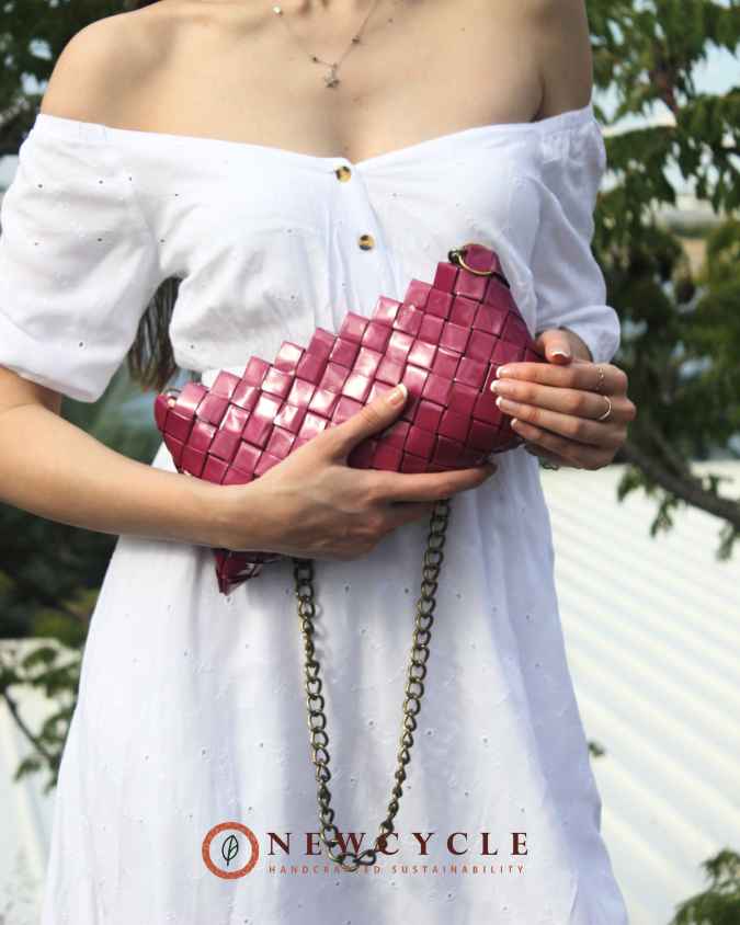 Fuchsia handmade woven purse shown close to the body with chain strap