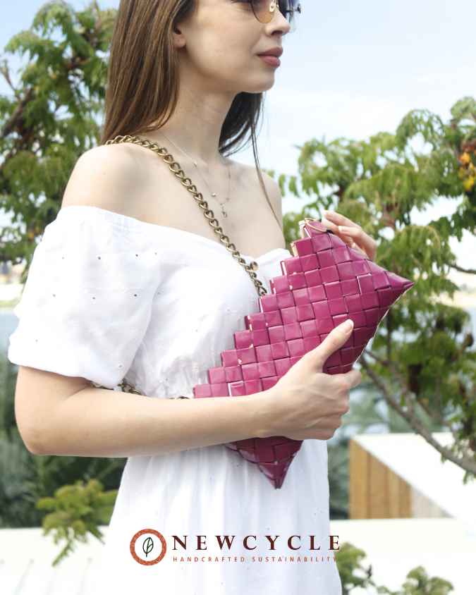 Model wearing a fuchsia woven shoulder bag with metal chain strap