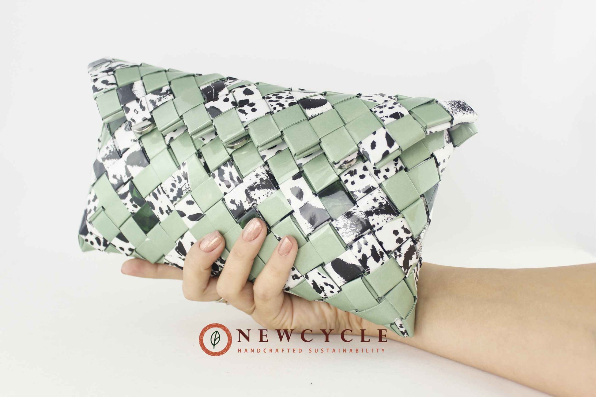Hand holding eco friendly green woven clutch with animal print