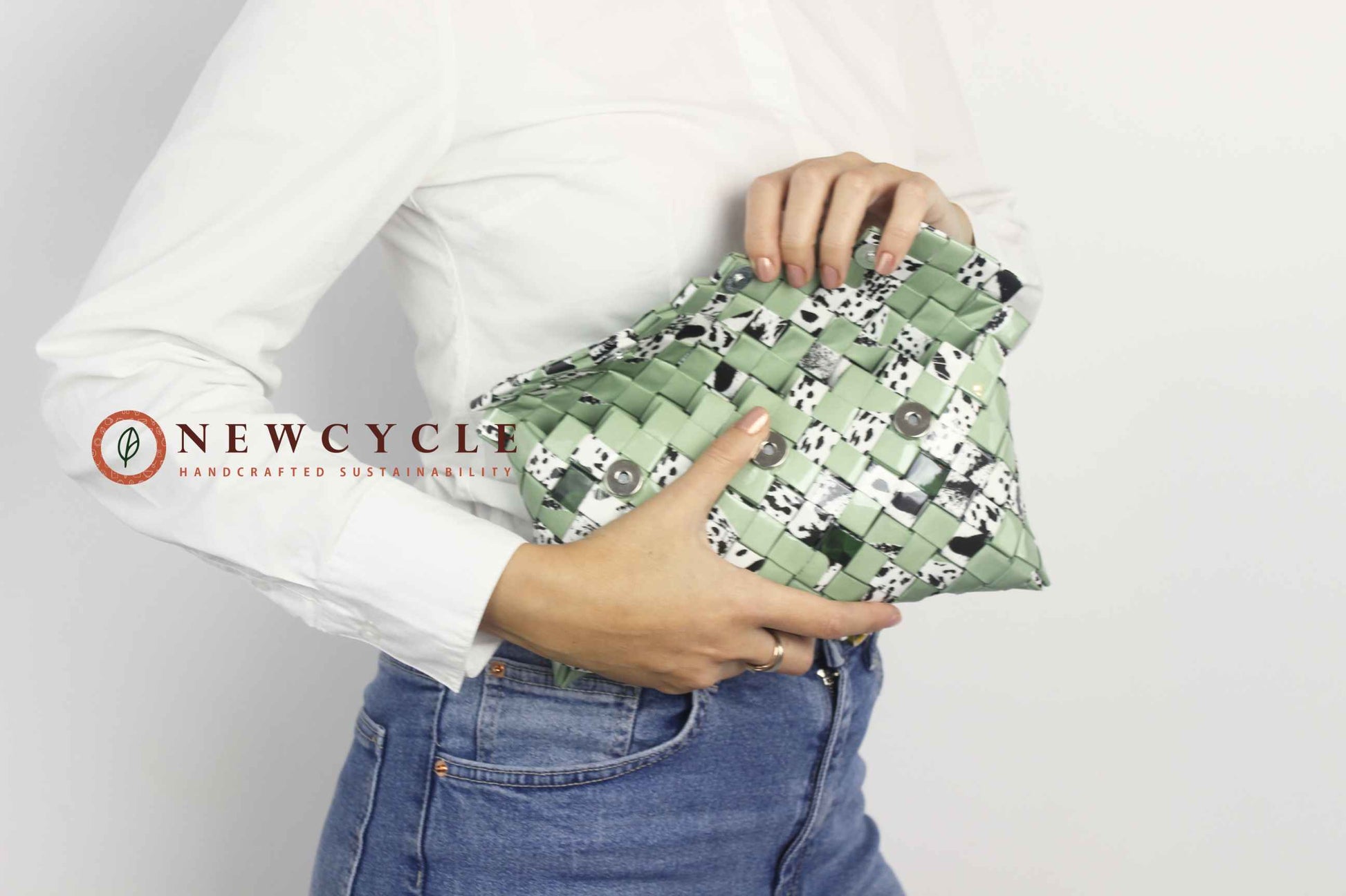 Woman holding green upcycled woven clutch with animal print