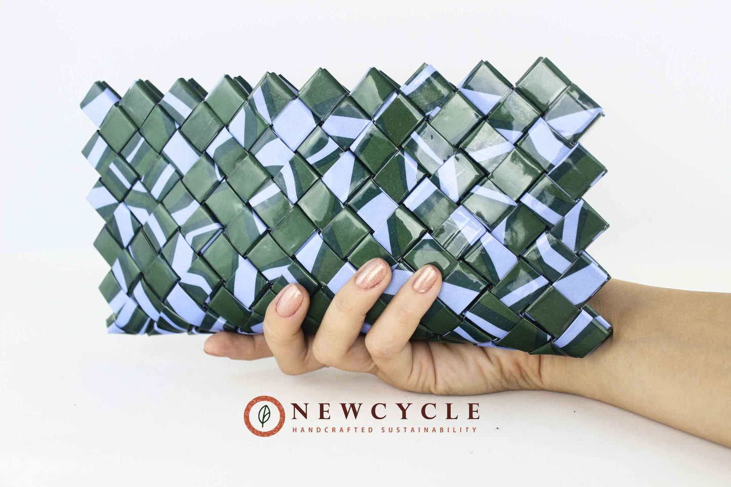 Hand holding a handmade upcycled woven clutch in forest green and powder blue, front view.