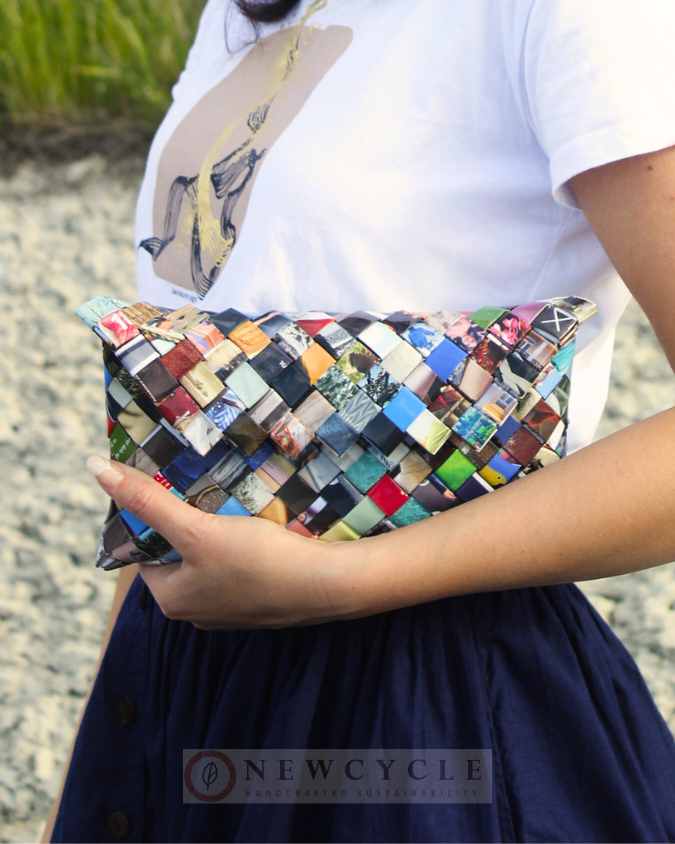 Handcrafted multicolor woven clutch held against a white blouse