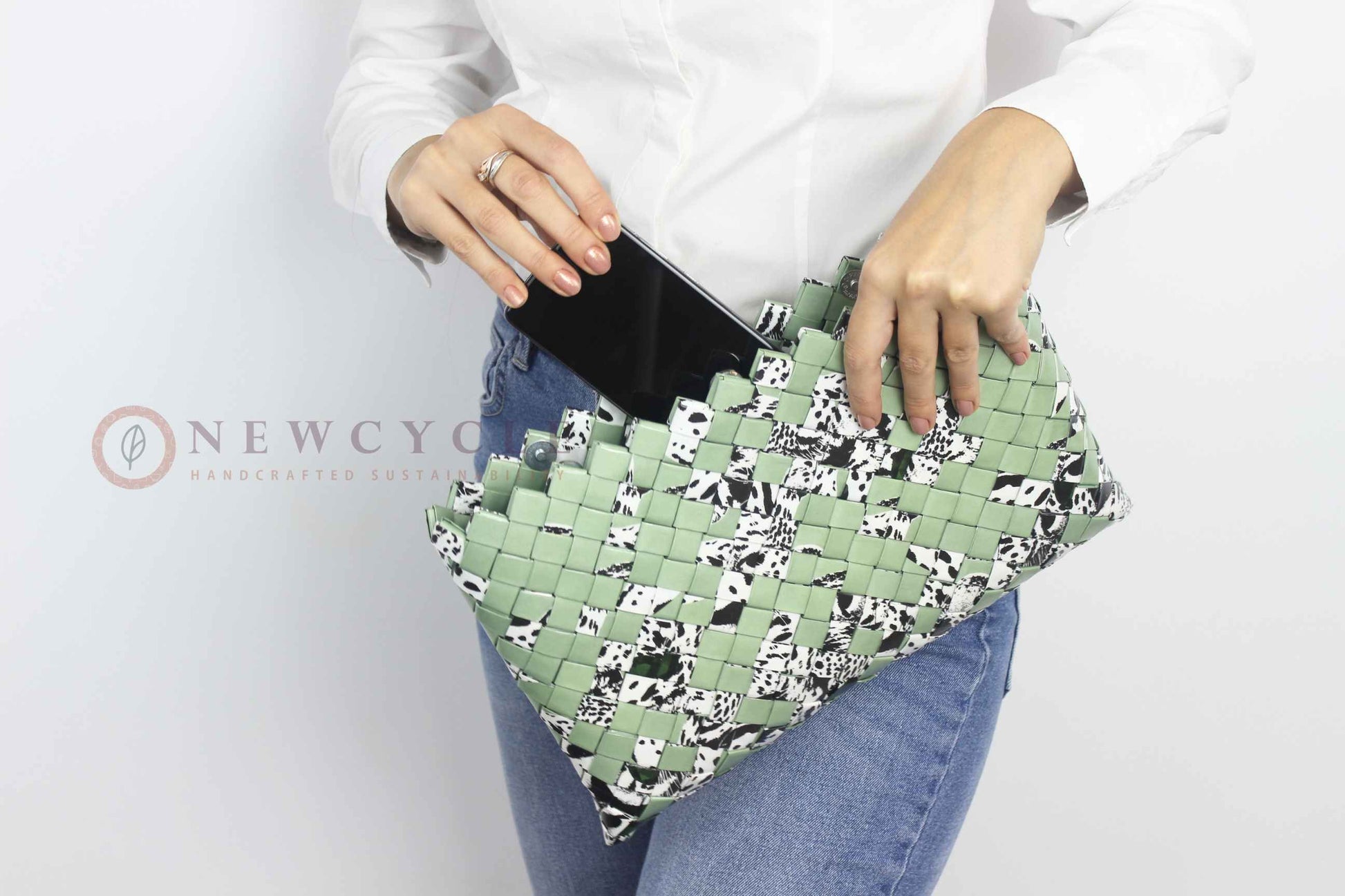 Woman holding an oversized green hand-woven clutch with animal print