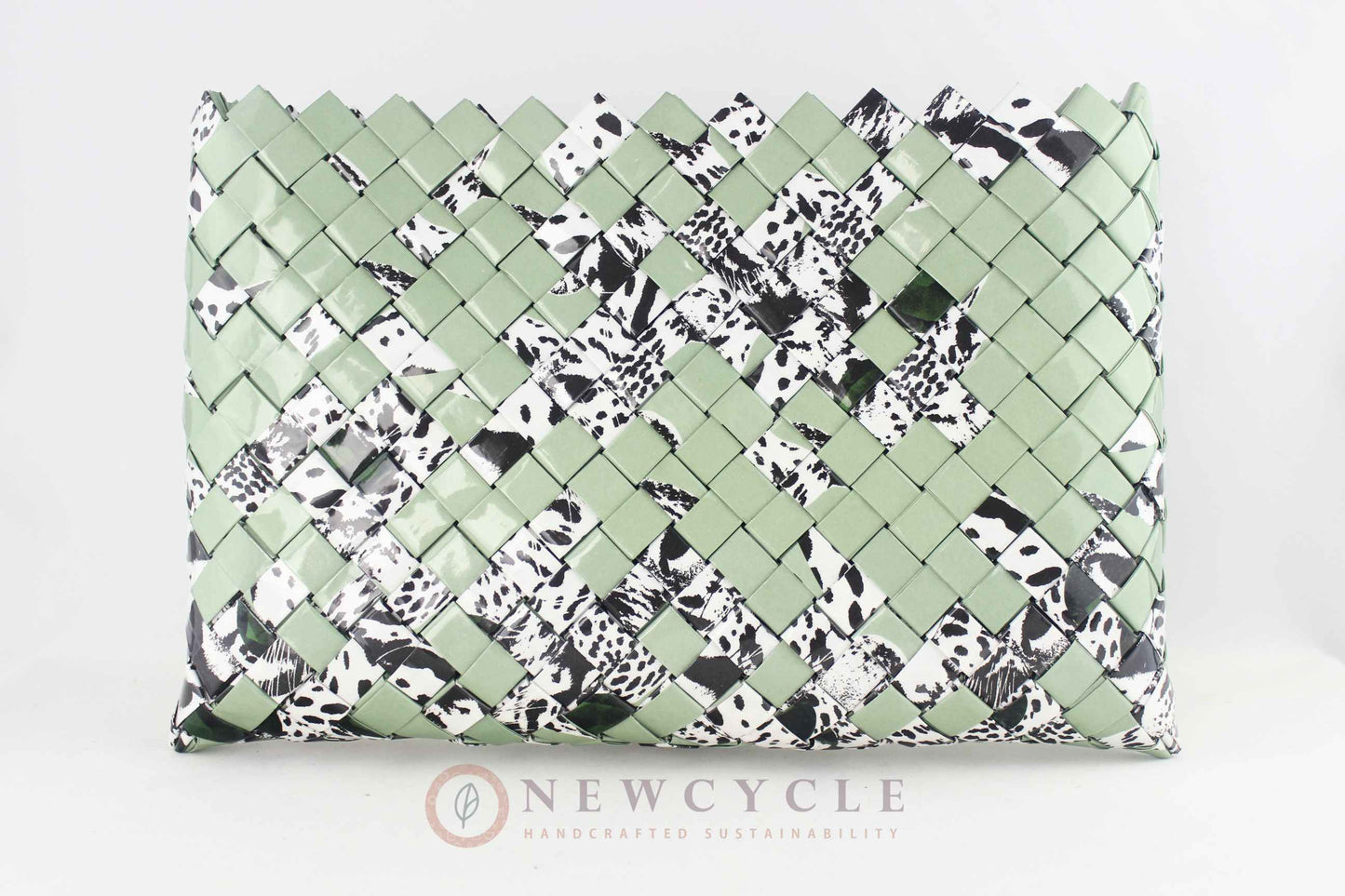 Oversized green woven clutch displayed on white background with animal print accents