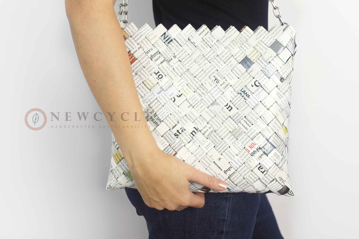 Woman holding an oversized newspaper-print woven shoulder bag