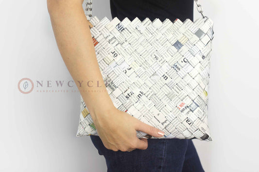 Woman holding an oversized newspaper-print woven shoulder bag