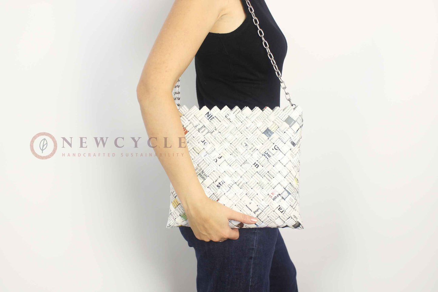Oversized newspaper-print woven shoulder bag worn on the shoulder