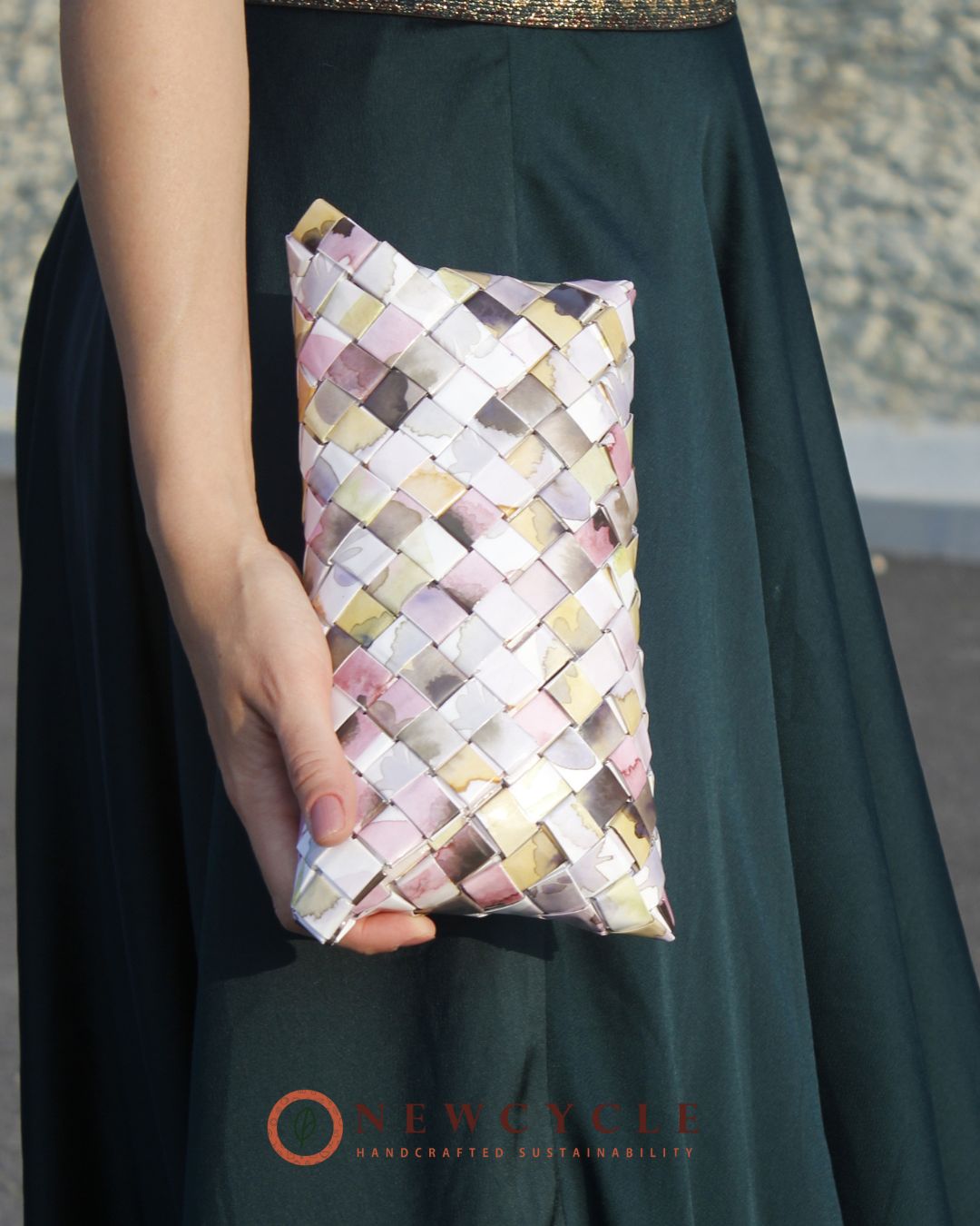 Pastel pink woven clutch held in hand for size reference