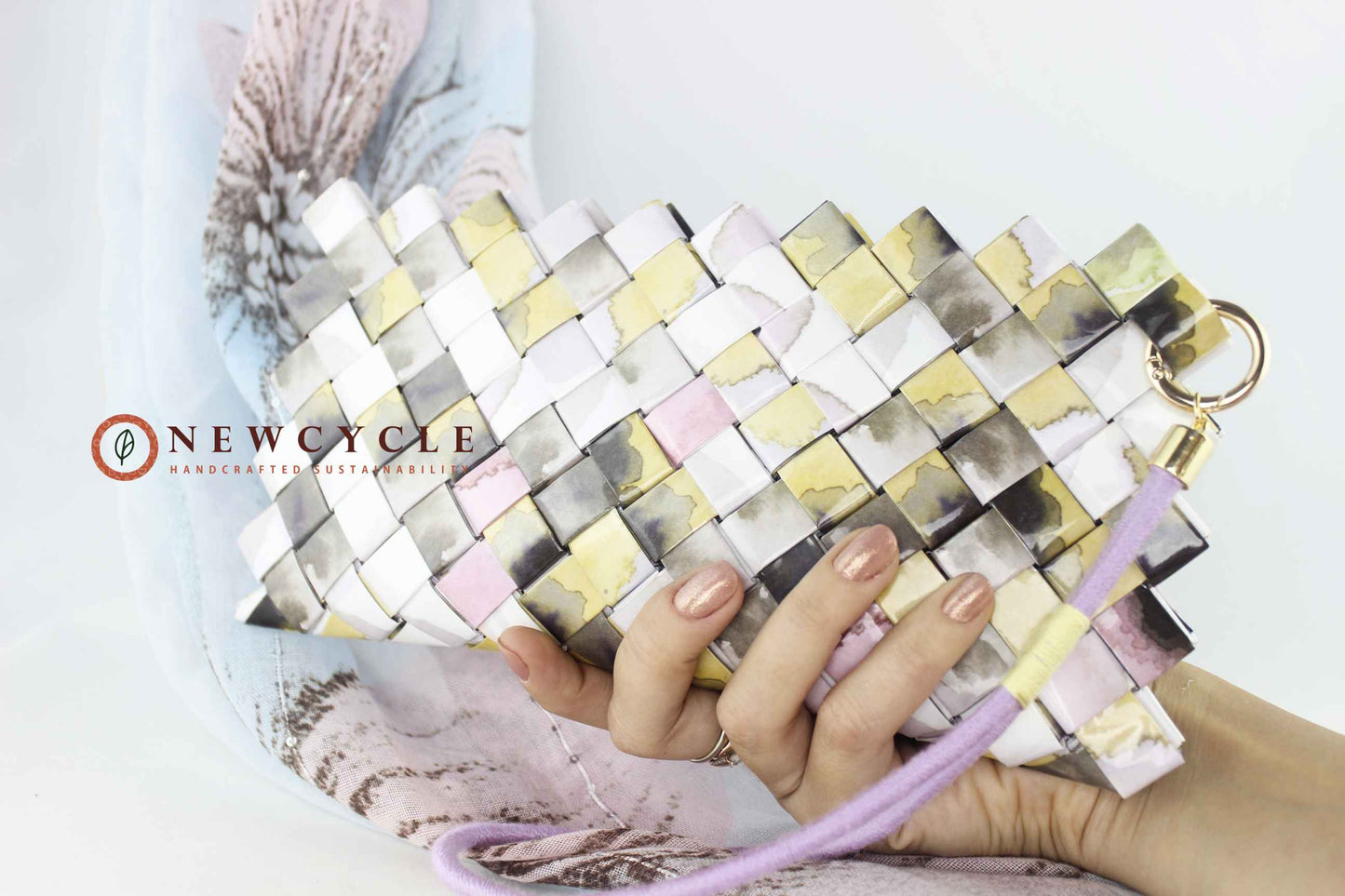 Hand holding pastel mosaic wristlet clutch – eco friendly woven purse