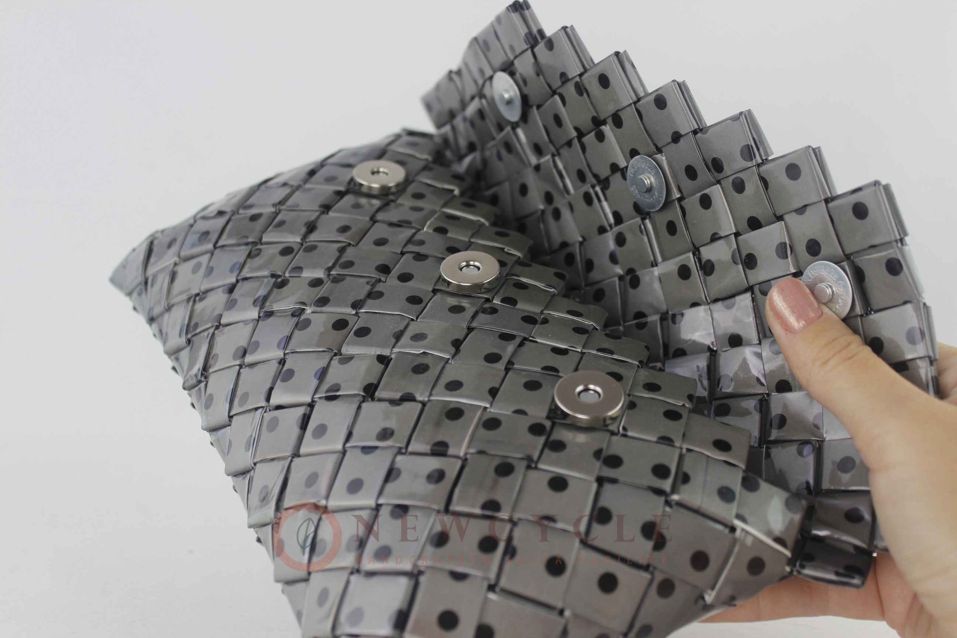 Black and grey polka-dot clutch shown in close-up while being held