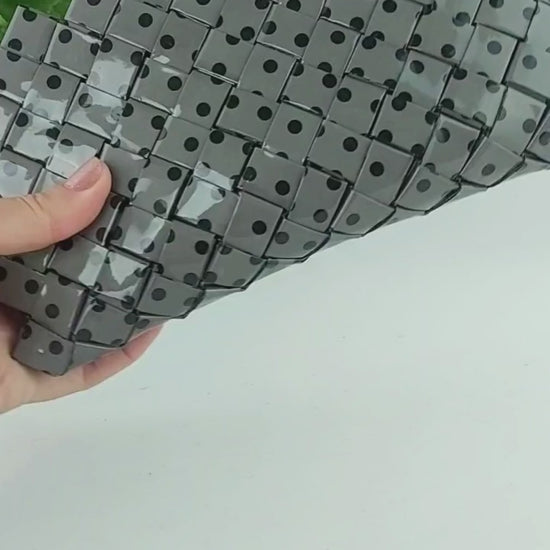 Video preview showing grey polka dot woven clutch in use