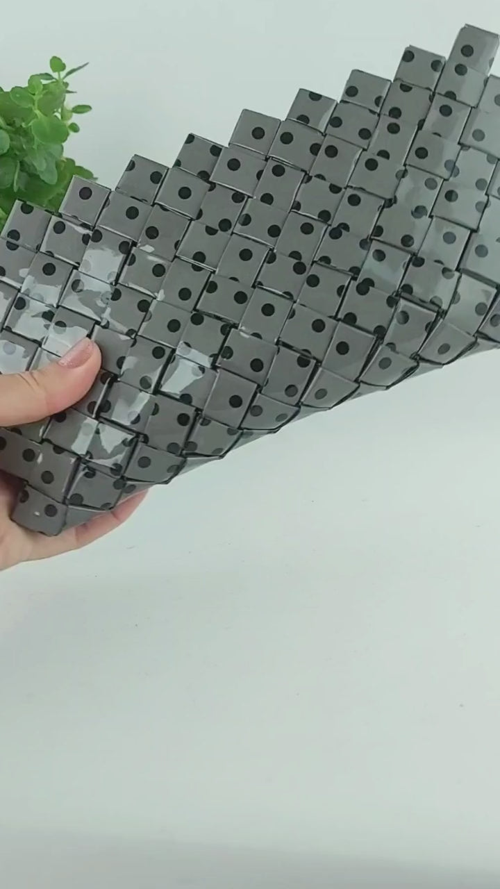 Video preview showing grey polka dot woven clutch in use