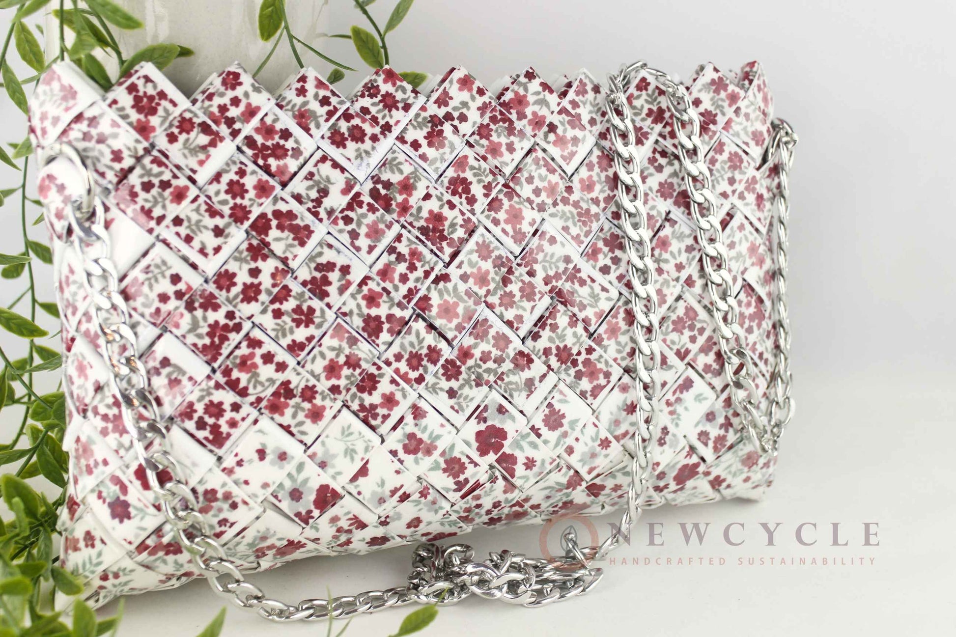 Red floral woven purse styled with greenery background