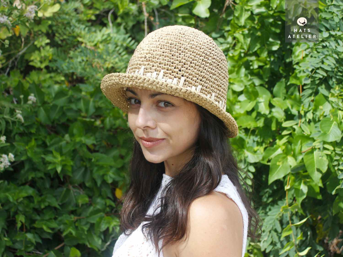 Boho short brim crochet raffia hat in natural straw, angled view on model