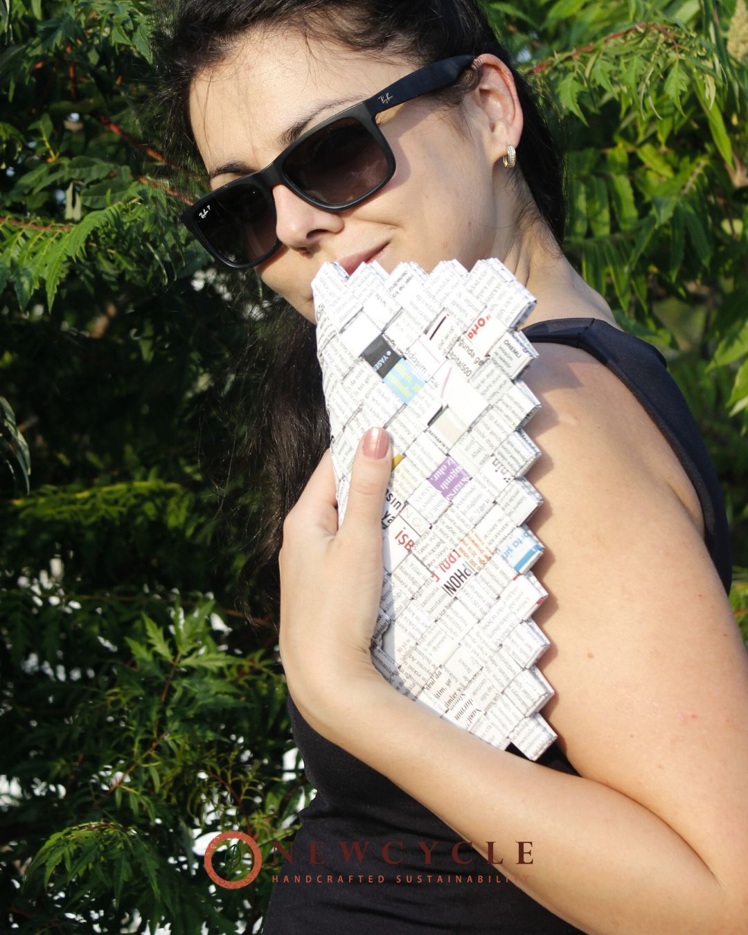 Woman styling a white newspaper mosaic clutch, unique upcycled fashion piece