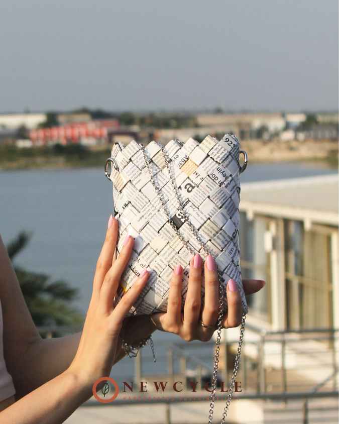 Upcycled woven purse with silver chain strap held in hands