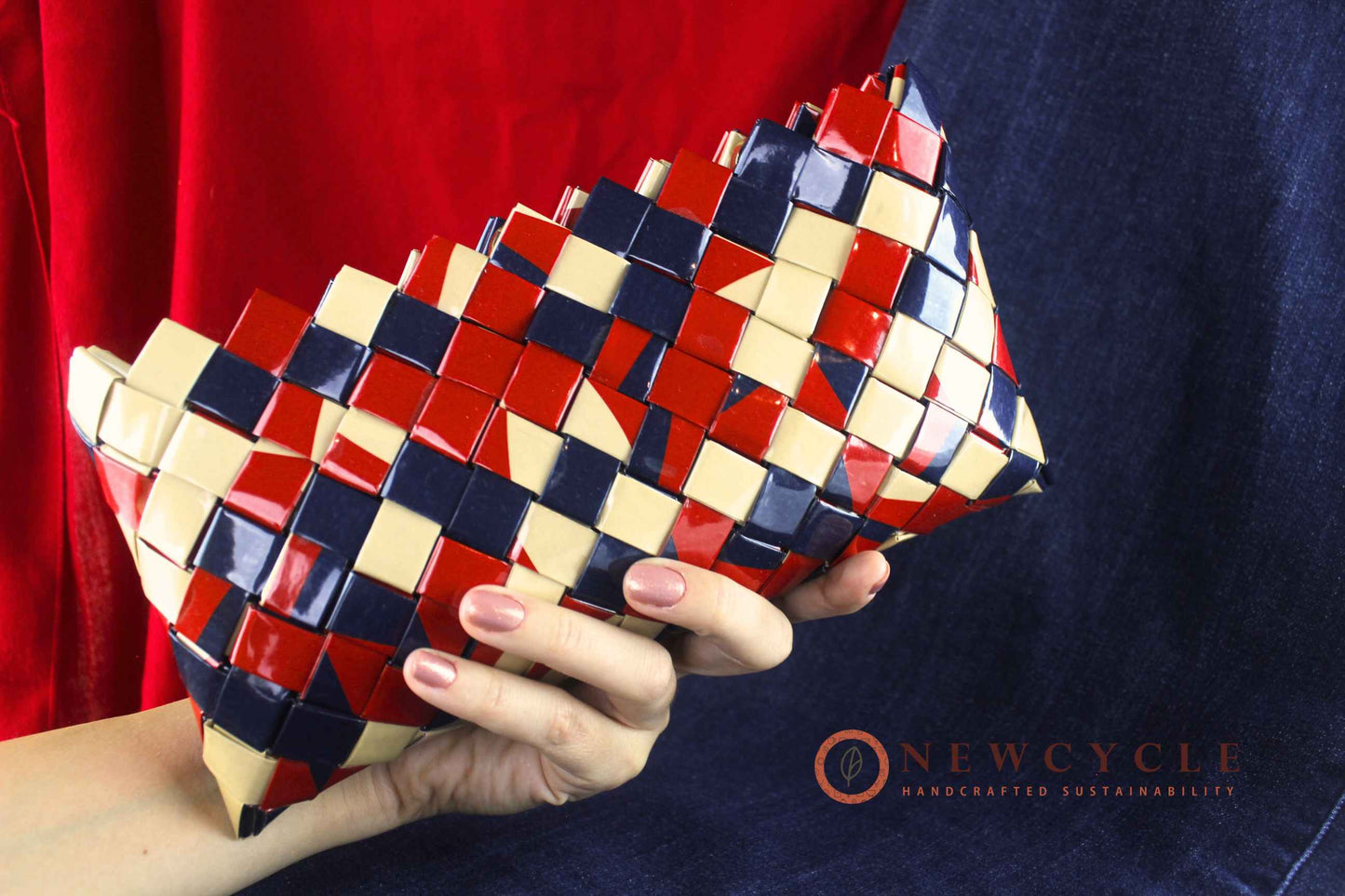 Hand holding red navy cream mosaic woven clutch